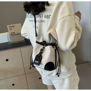 Detail view of contrast bucket bag with woven texture, drawstring and leather strap