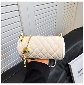 Close-up of quilted cream cylinder bag with golden chain and ball adjustment buckle