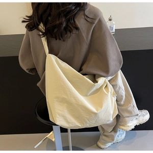 Détail d'un grand sac fourre-tout crème porté en bandoulière avec une texture drapée fluide