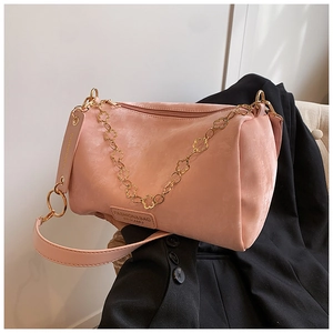 Detailed macro view of pink Boston bag with golden floral chain and leather strap