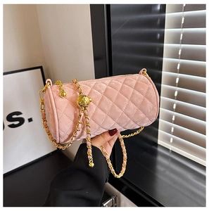 Macro detail of pink velvet quilted cylinder bag with gold chain and ball buckle