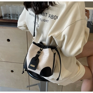 Detail of a chic black and white bucket bag featuring woven texture and leather trim