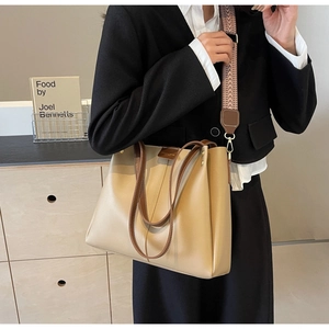 Detail view of large tote bag with wide geometric strap and beige-brown leather trim