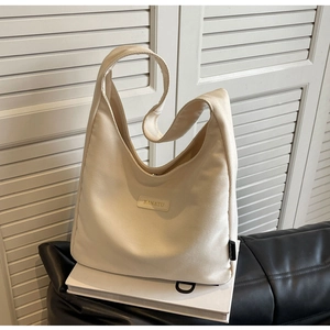 Detail of beige corduroy hobo bag texture with BANATU leather logo on white books