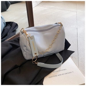 Detail of light blue crossbody bag with gold floral chain and wide shoulder strap