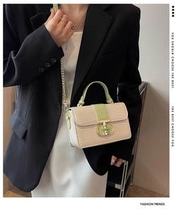 Detail of crocodile pattern crossbody bag with green contrast handle and chain strap