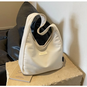 Detailed texture of beige corduroy hobo bag with Banatu logo on stone pedestal