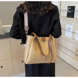 Detail of light brown tote bag with geometric wavy strap on a model's shoulder