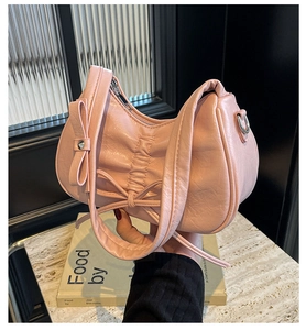 Detail of light pink pleated Hobo bag with decorative bow and silver metal hardware