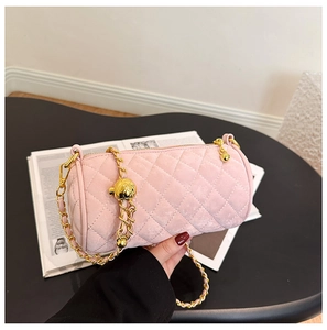 Macro shot of pink quilted cylinder bag featuring a gold chain and spherical metal buckle