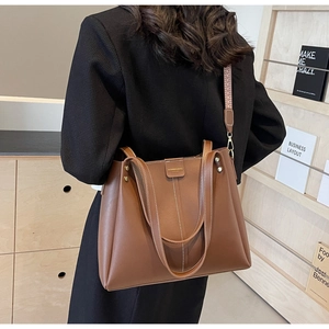 Détail d'un sac cabas marron avec coutures verticales et bandoulière jacquard colorée