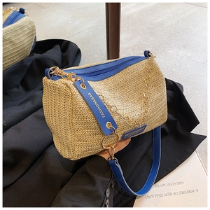 Detail of woven Boston bag featuring royal blue leather trim and golden chain accent