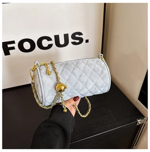 Detail of light blue velvet cylinder bag with quilted texture and gold chain strap