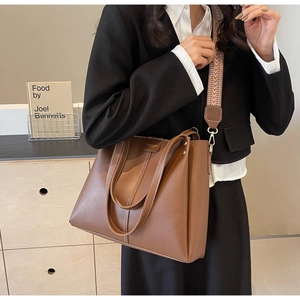 Borsa tote in pelle marrone con tracolla larga intrecciata mostrata in stile di vita