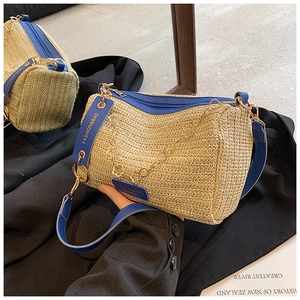 Detail of woven straw bag with dark blue leather trim and golden floral metal chain