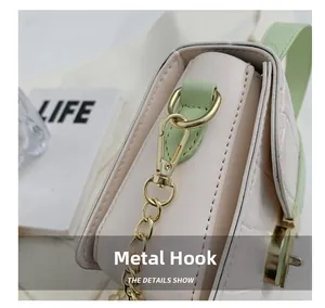 Close-up of golden metal hooks and crocodile-embossed leather on stylish shoulder bag