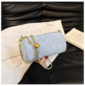 Macro shot of light blue quilted suede cylinder bag with gold chain and sphere charm