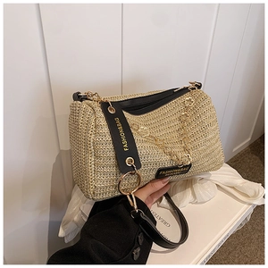 Close-up of woven straw Boston bag with gold chain and branded letter strap detail