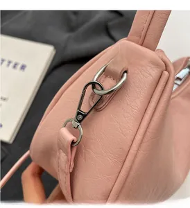 Close-up of pink pleated handbag showing silver metal swivel hook and lychee texture
