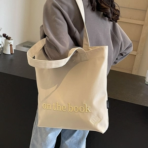 Chic off-white canvas tote bag with 'on the book' embroidery for casual daily use