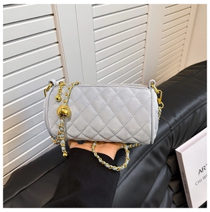 Close-up of quilted cylinder bag featuring golden chain strap and round metal buckle