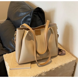 Detail of beige tote bag with brown leather trim and patterned woven shoulder strap