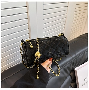 Detailed close-up of a mini quilted velvet cylinder bag with gold chain and ball charm