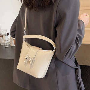 Sac seau chic blanc crème avec nœud argenté porté en bandoulière par un mannequin