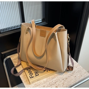 Close-up of beige tote bag featuring vintage woven strap and premium metal rivets detail