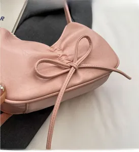 Detail of light pink shoulder bag featuring a large bow and elegant pleated PU leather texture