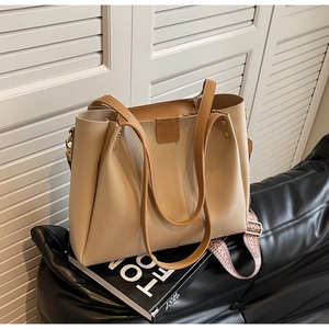 Close-up of beige lychee grain tote with a patterned woven shoulder strap and metal buckle