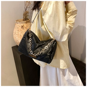 Detail of black Boston bag with golden flower chain and fashion label on warm background