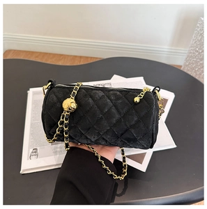 Detailed close-up of quilted velvet cylinder bag with adjustable gold ball chain strap