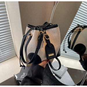 Detail of woven bucket bag featuring cream texture, black leather trim and gold hardware