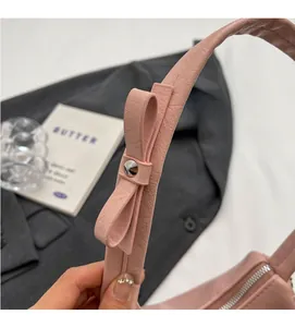 Close-up of pink leather handbag showing bow knot detail and silver rivet hardware