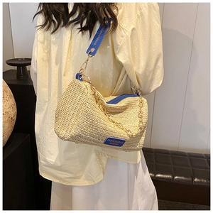 Close-up of woven straw Boston bag with blue leather trim and golden metal chain strap