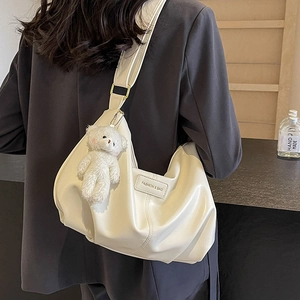 Chic pleated cream tote bag with gold buckle and cute bear pendant shown on model