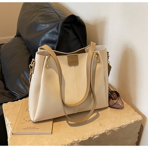 Detail of cream tote bag featuring brown handles and vintage geometric fabric wide strap