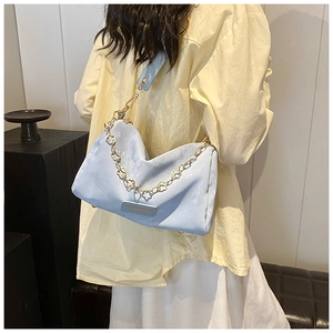 Detail of light blue Boston bag with golden flower chain and wide fabric strap
