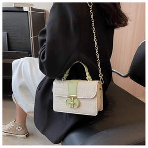 Detailed shot of crocodile embossed flap bag with gold twist lock and metal chain strap