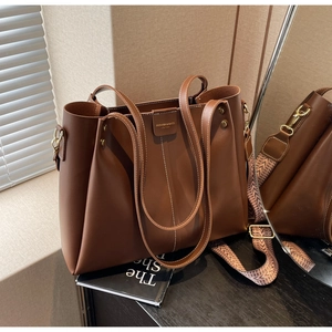 Detail of brown leather tote bag with stylish patterned wide shoulder strap for commuting