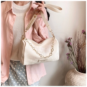 Detail of cream Boston bag with golden flower chain and leather brand tag decoration