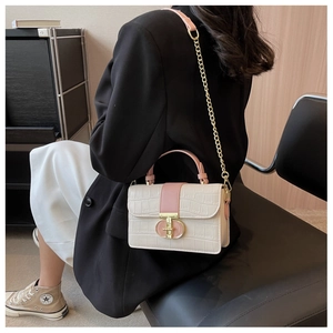 Model wearing a cream and pink croc-effect small square bag with chain strap and gold clasp