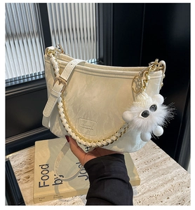 Detail of cream bucket bag with gold chain, adjustable strap and cute plush charm