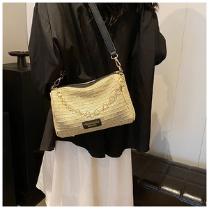 Detail of beige straw Boston bag with woven texture, black strap and floral gold chain