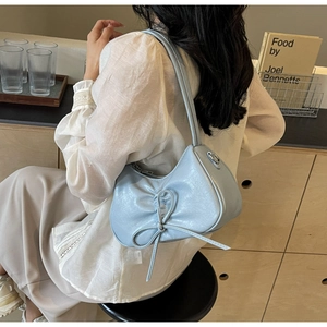 Detailed view of light blue pleated underarm bag with decorative bow and PU leather texture