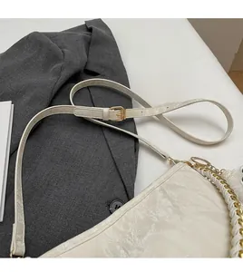 Detail of adjustable cream leather strap with gold buckle on elegant shoulder bucket bag