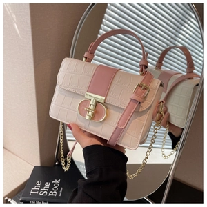 Detail of pink and beige crossbody bag with crocodile texture and gold metal twist lock
