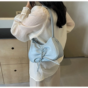 Close-up of light blue pleated underarm bag with delicate bow knot and thin shoulder strap