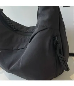 Detail of lightweight black nylon fabric and braided zipper pull on casual crossbody bag